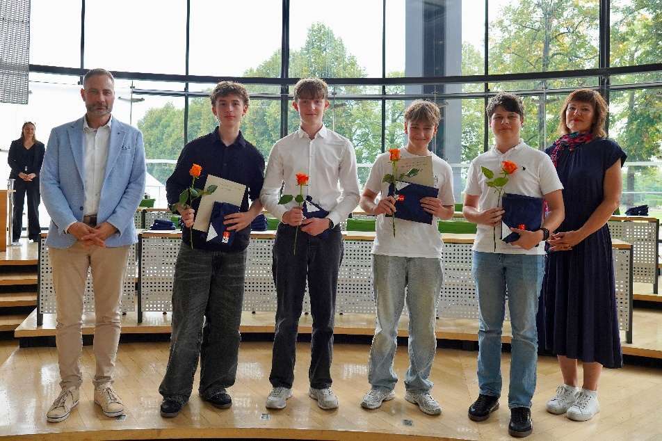 Die vier Schüler des Teams Latein mit Urkunden und Rosen im Plenarsaal des Sächsischen Landtages, neben ihnen zwei Erwachsene.